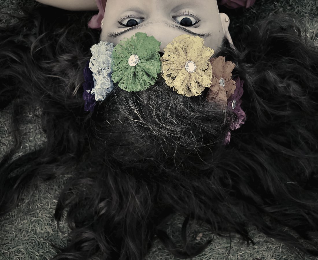 A girl lying in the grass with lace flowers woven through her hair