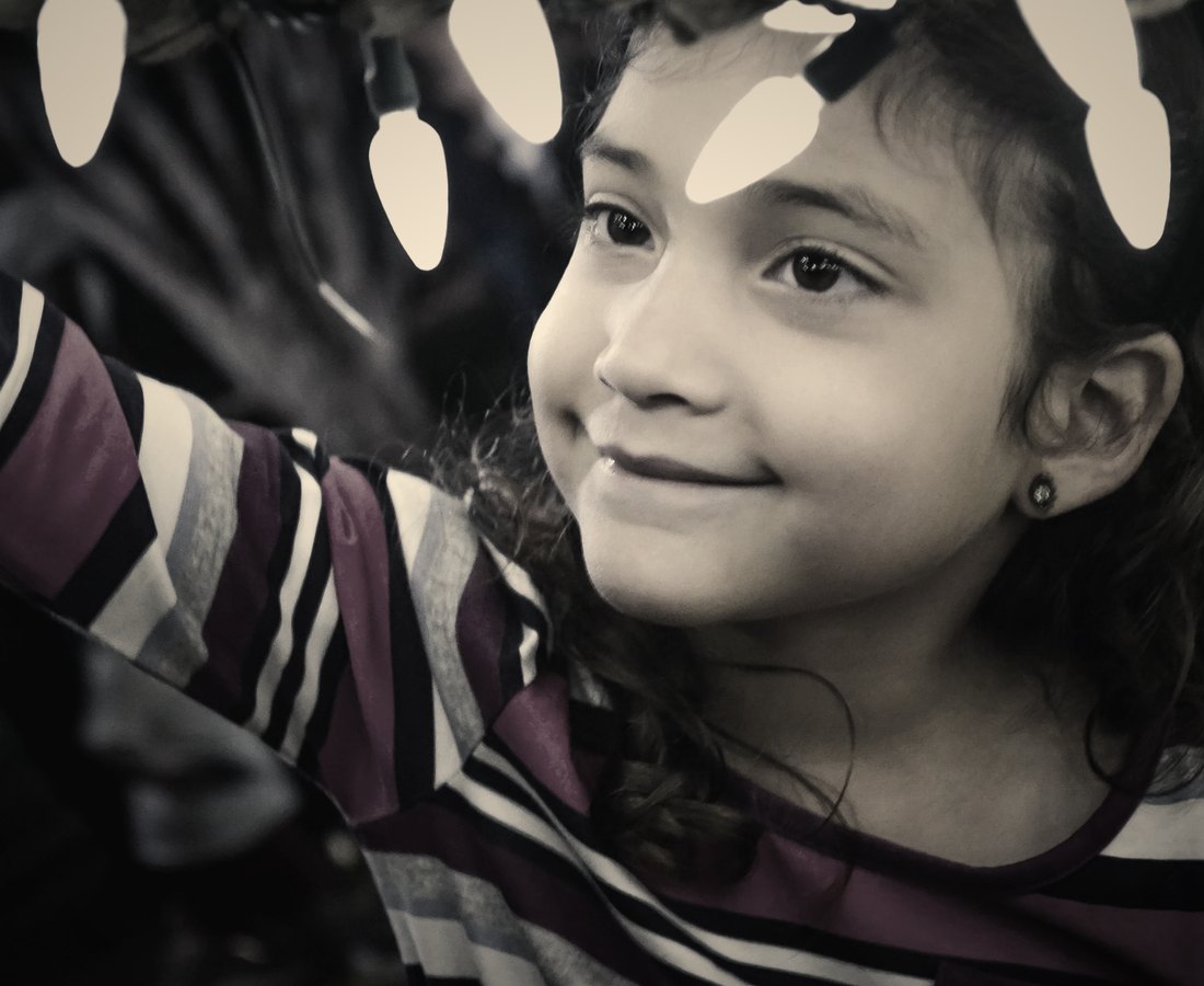 A girl smiling beneath a strand of glowing lights
