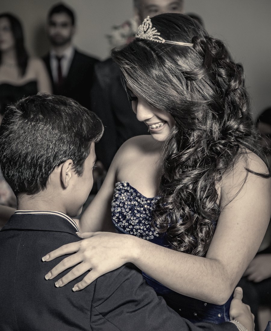 A girl in a tiara embracing her younger brother at her quinceañera